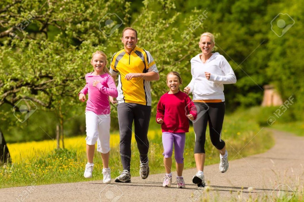 17657227 happy family with two girls running or jogging for sport and better fitness in a meadow in summer - Futbolinfo.az